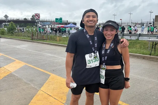 qc_5krace_600x400 Chanh and Quynh smiling after completing a race, wearing medals and race bibs at the finish line on a rainy day