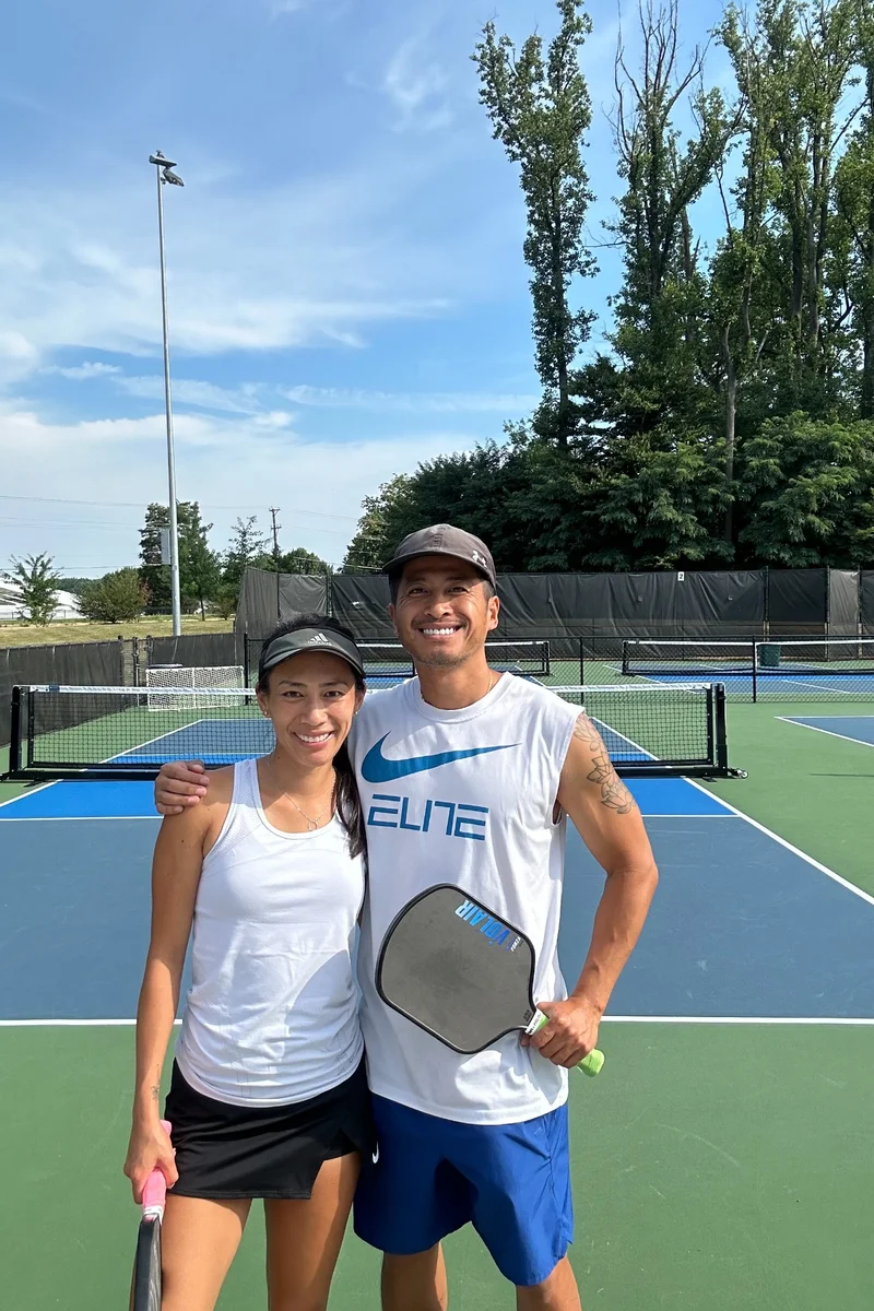 TeamFit40 Founders – Chanh & Quynh on the court Chanh and Quynh smiling on a pickleball court, staying active together after 40